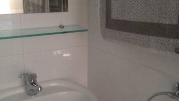 Un baño con un lavabo blanco, repisa de vidrio, toallero y espejo.