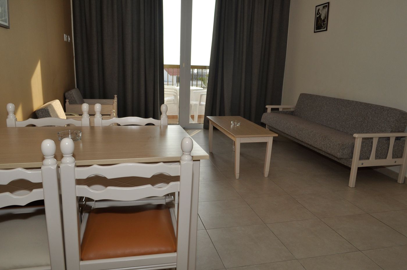 A living room with a dining table, chairs, a sofa, and a small table.