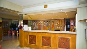 A reception desk with a 'No Smoking' sign, a mural of historical figures, and a seating area with chairs. - Christabelle Hotel Apartments (Ayia Napa)