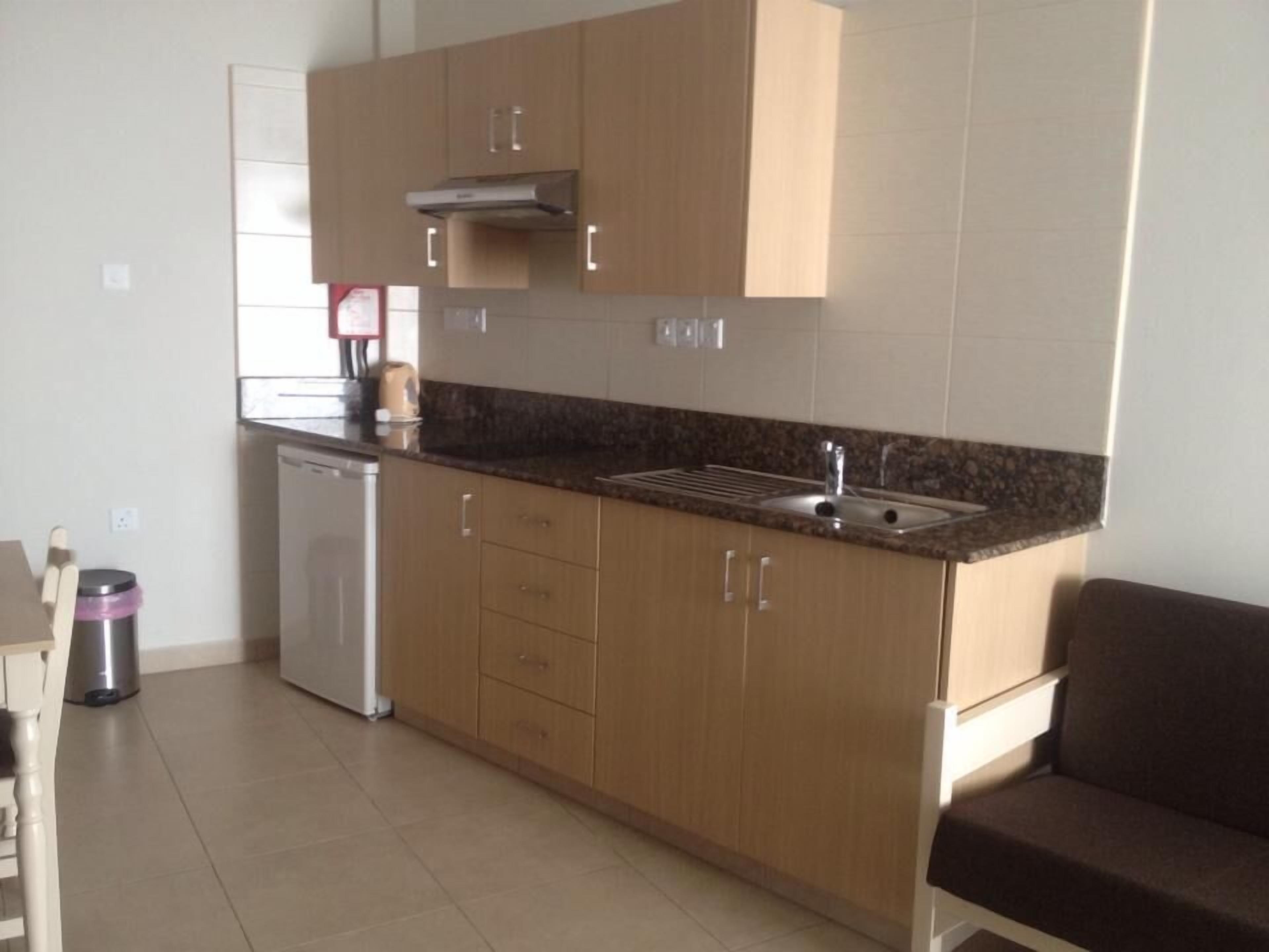 Una cocina funcional con armarios de madera, horno empotrado y pileta de acero inoxidable.