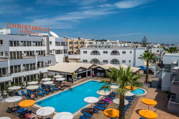 Relax by the rooftop pool surrounded by sun loungers and umbrellas, with a covered seating area nearby.