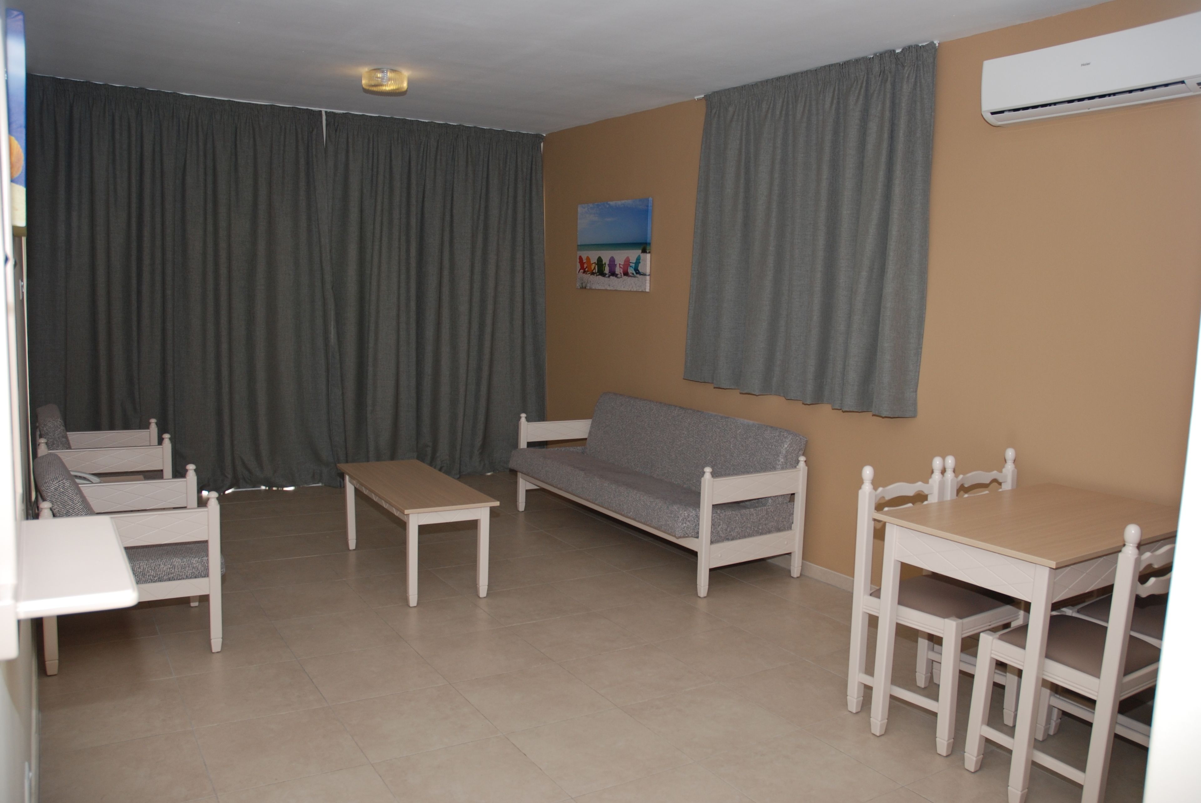 Een woonkamer met een bank, twee stoelen, een tafel en een schilderij aan de muur.