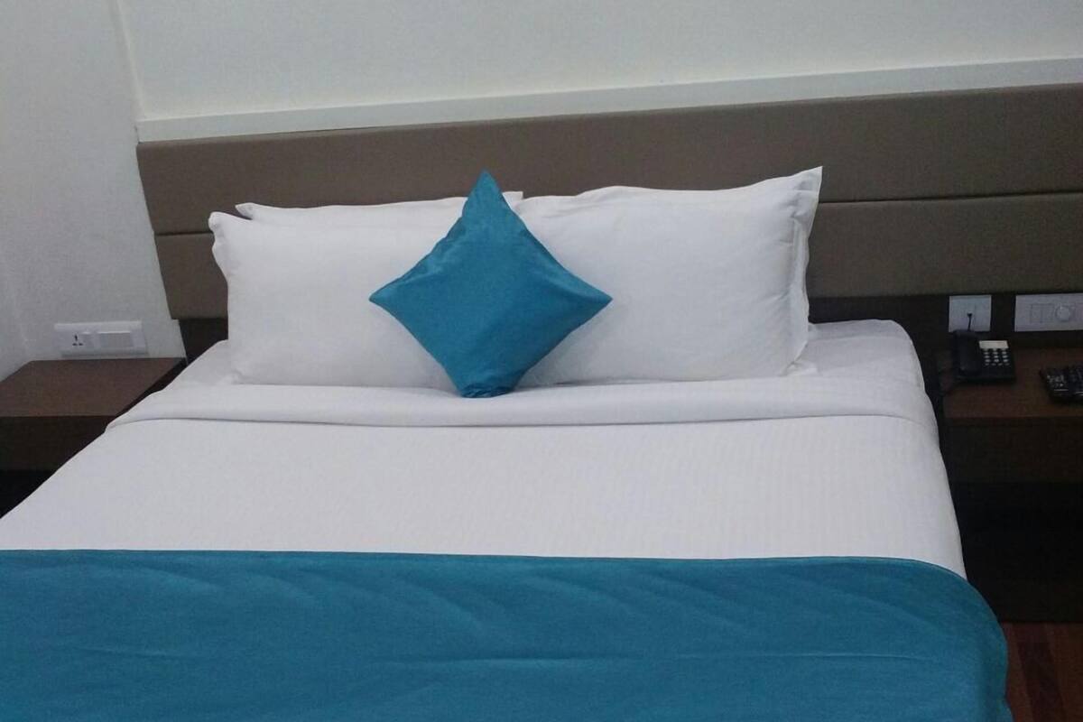 Een hotelkamer met een bed, nachtkastje en een stopcontact.