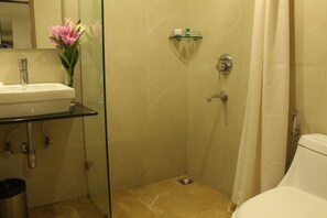 A bathroom with a glass shower enclosure, a white sink, and a toilet.