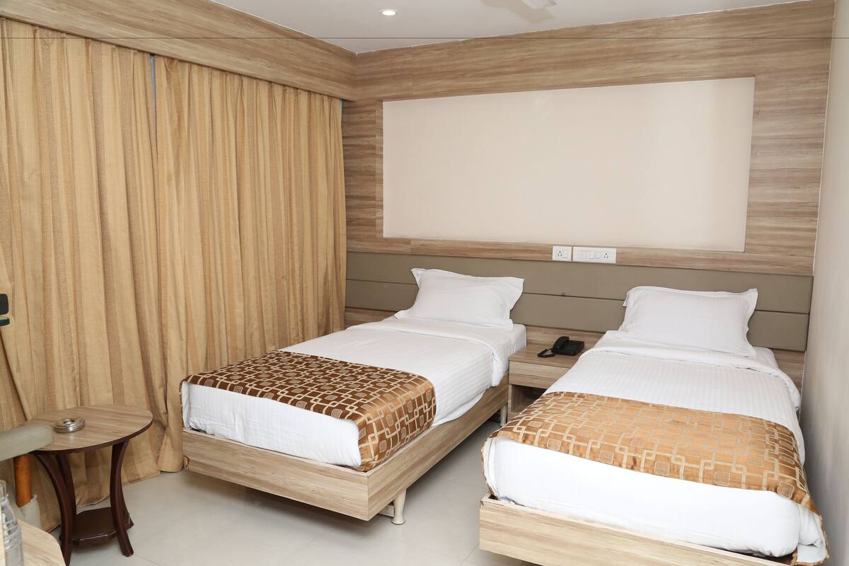 Een hotelkamer met twee bedden, een bureau en een groot raam.