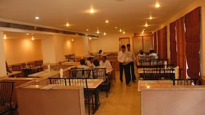 Un restaurant avec plusieurs tables et chaises, un comptoir et quelques personnes.