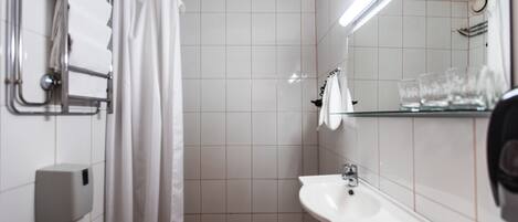 Ein Badezimmer mit Waschbecken, Spiegel und Duschbereich mit Vorhang.