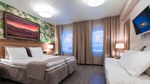 Una camera d'albergo con un letto grande, un letto più piccolo, una TV e un quadro appeso al muro.