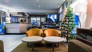 Una hall con due tavoli rotondi, un albero di Natale e uno schermo televisivo.