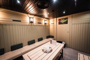 A wooden dining table with a tray of candles and a menu. There are several benches with cushions along the wall. - Hotel Aakenus (Rovaniemi)