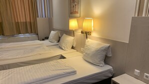 Une chambre d’hôtel avec deux lits, une table de chevet, une lampe et un tableau au mur.