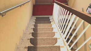 Un escalier recouvert d’une moquette rouge, doté d’une rampe blanche et d’un revêtement de sol texturé.