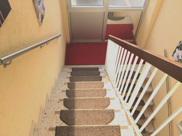 A staircase with a red carpet, white railing, and a textured floor. - Hotel New Fair Munich Messe (Munich)