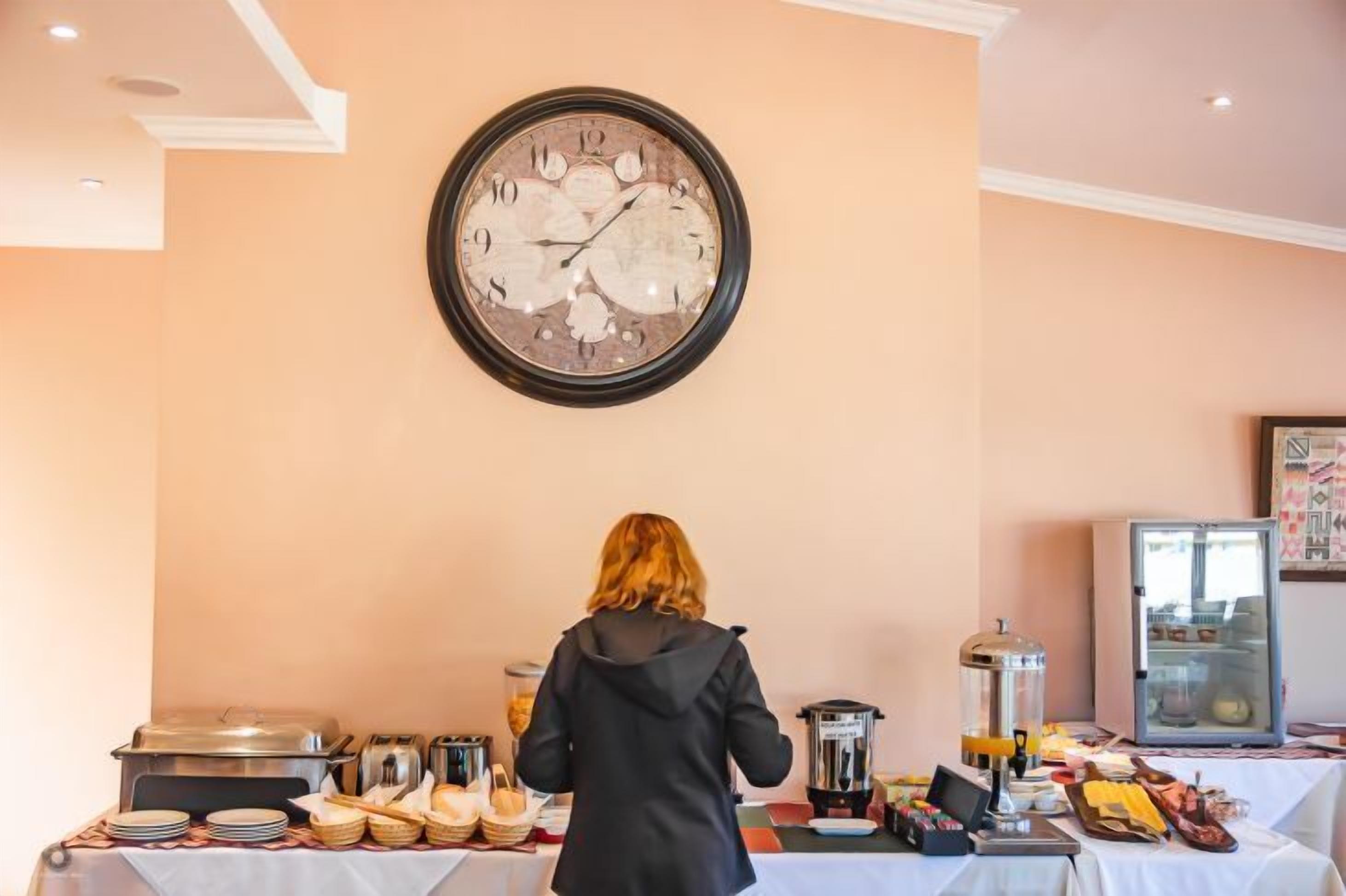 A buffet setup with various food items and a clock on the wall.