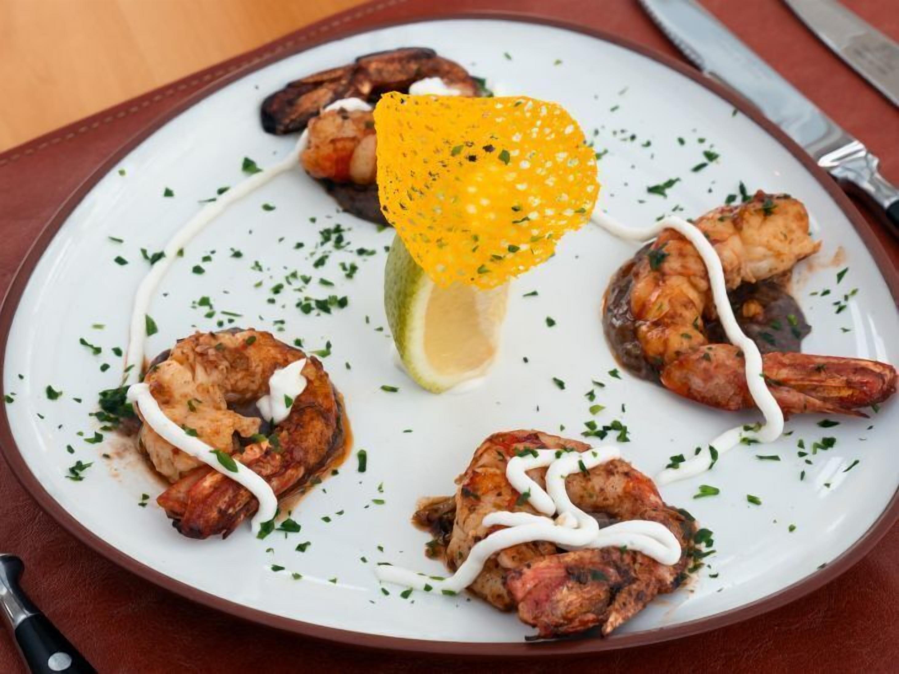 A plate of food with shrimp and a lemon wedge.