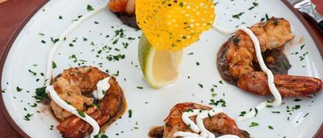 A plate of food with shrimp and a lemon wedge.