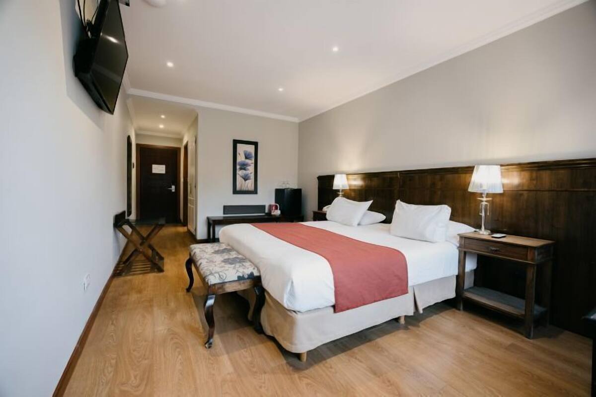 Une chambre d’hôtel avec un grand lit, des tables de chevet, un bureau et un téléviseur fixé au mur.