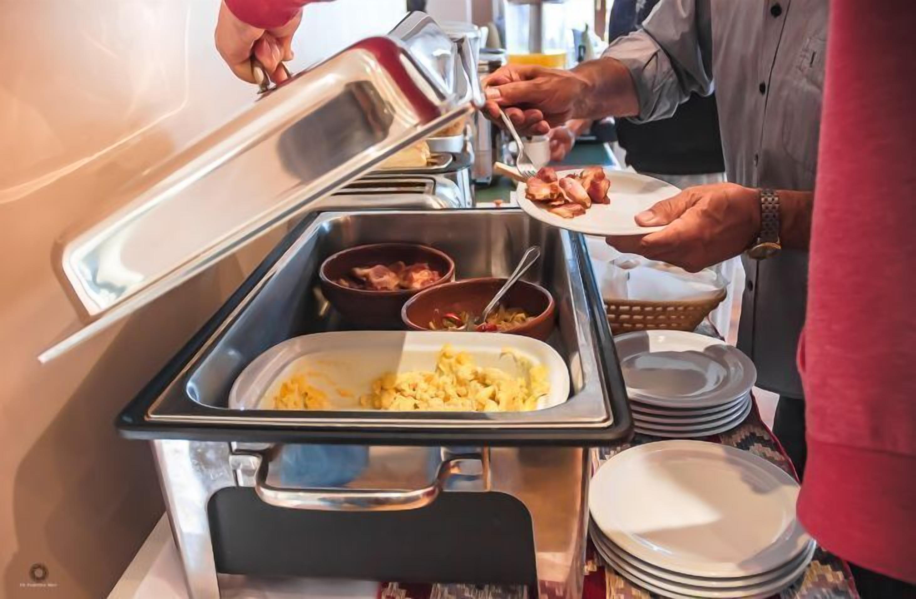 A buffet setup with various food items and utensils.