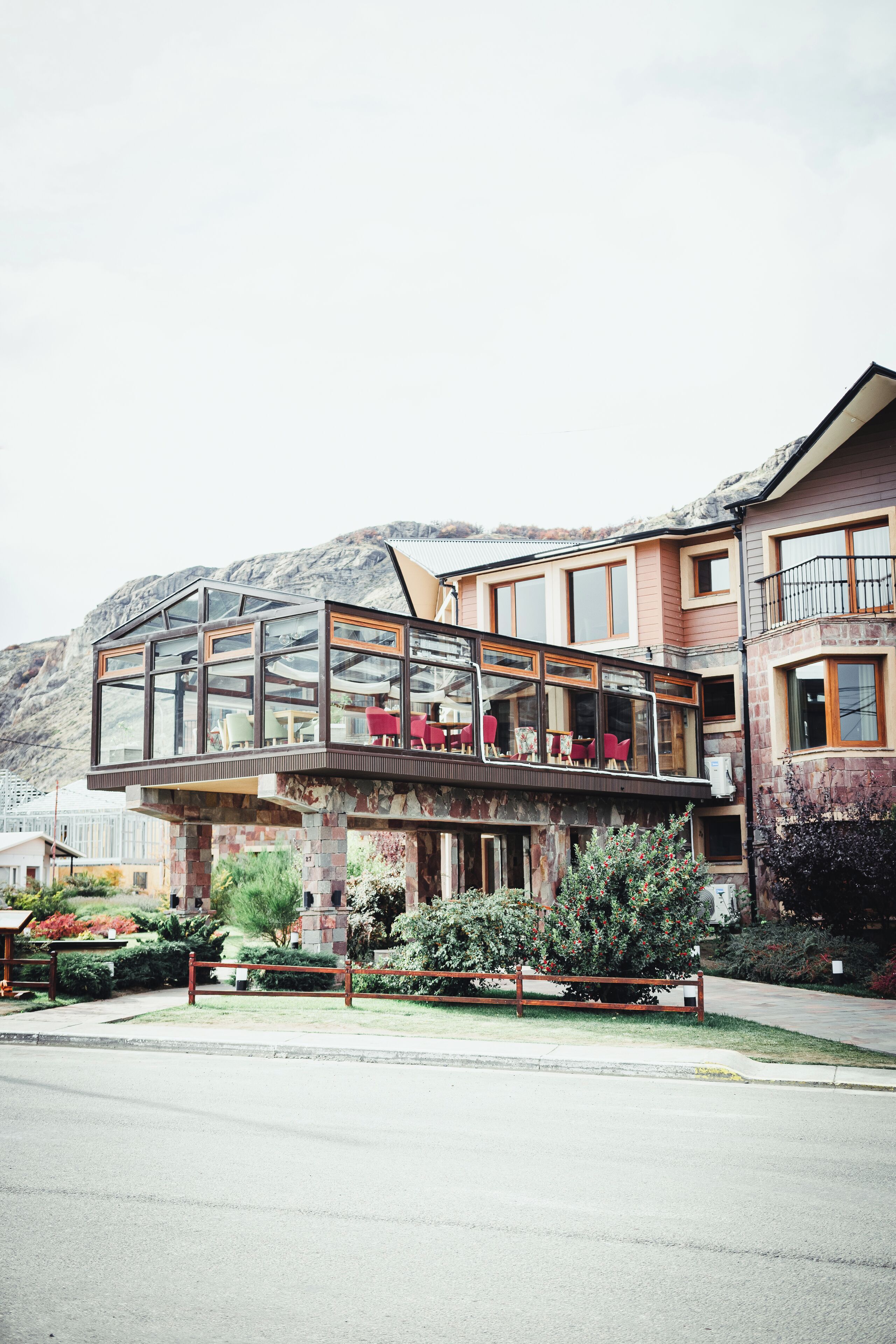 A modern building with a glass conservatory, red chairs, and a stone base.