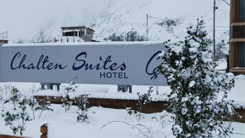 Señal de Chalten Suites Hotel con un fondo nevado.
