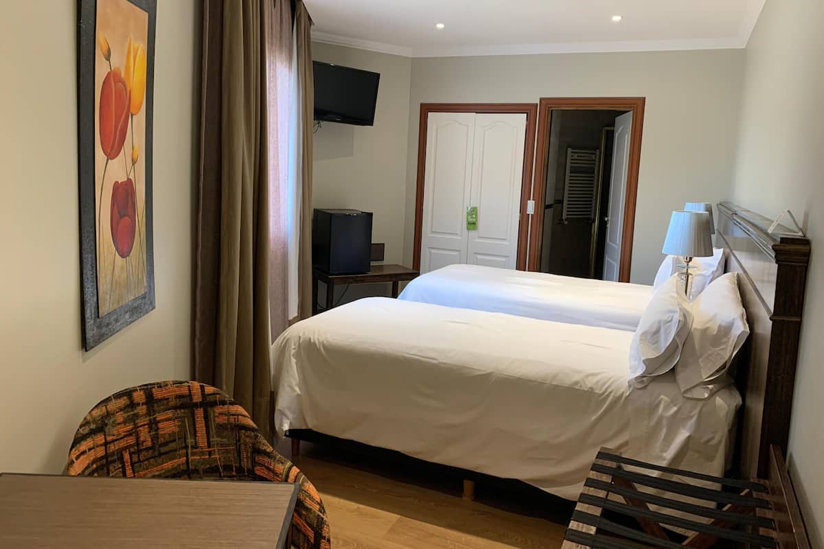 Une chambre d’hôtel avec deux lits, une télévision, un bureau et une chaise.