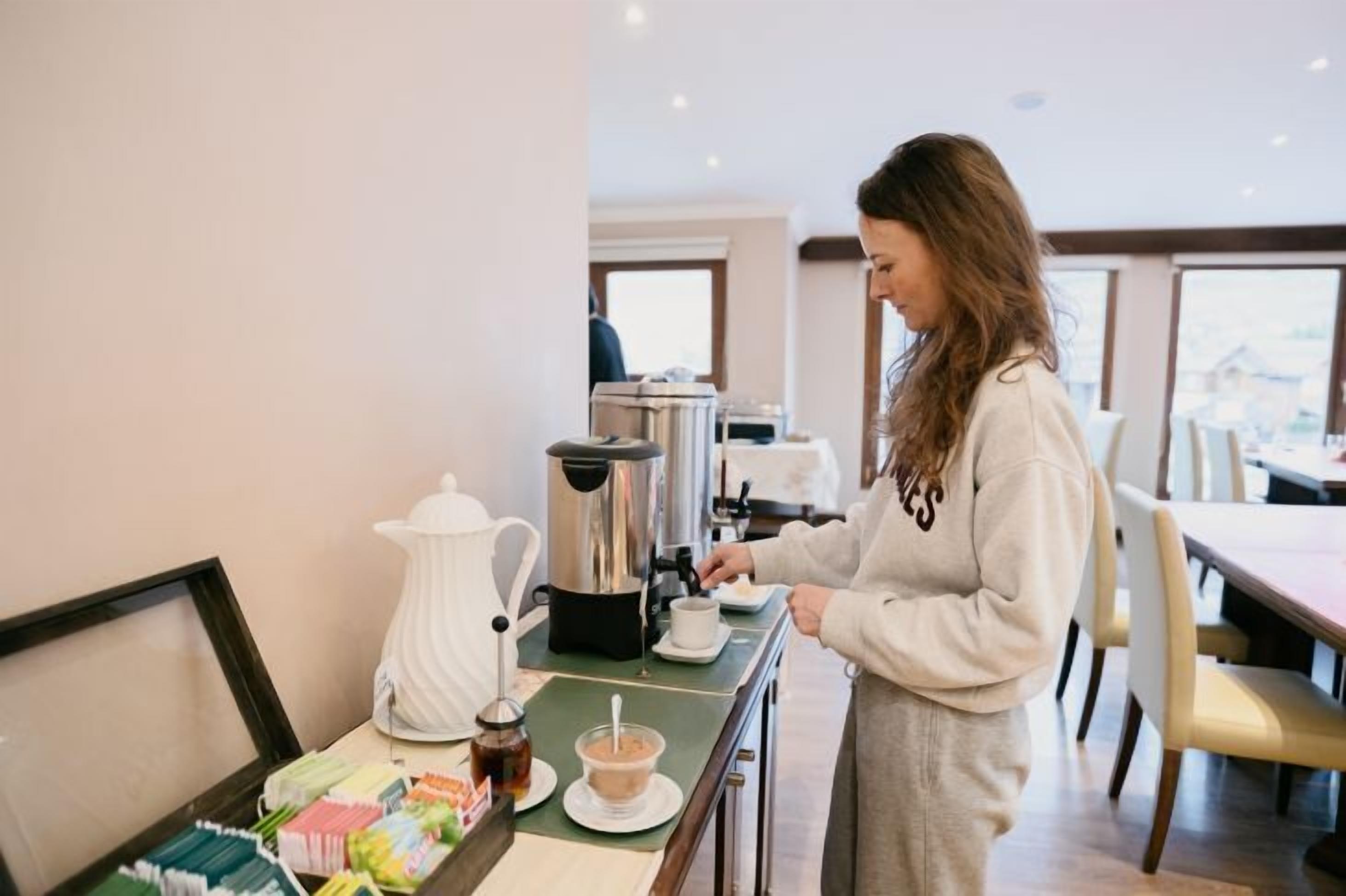 A person preparing coffee in a modern kitchen with a view of the city.