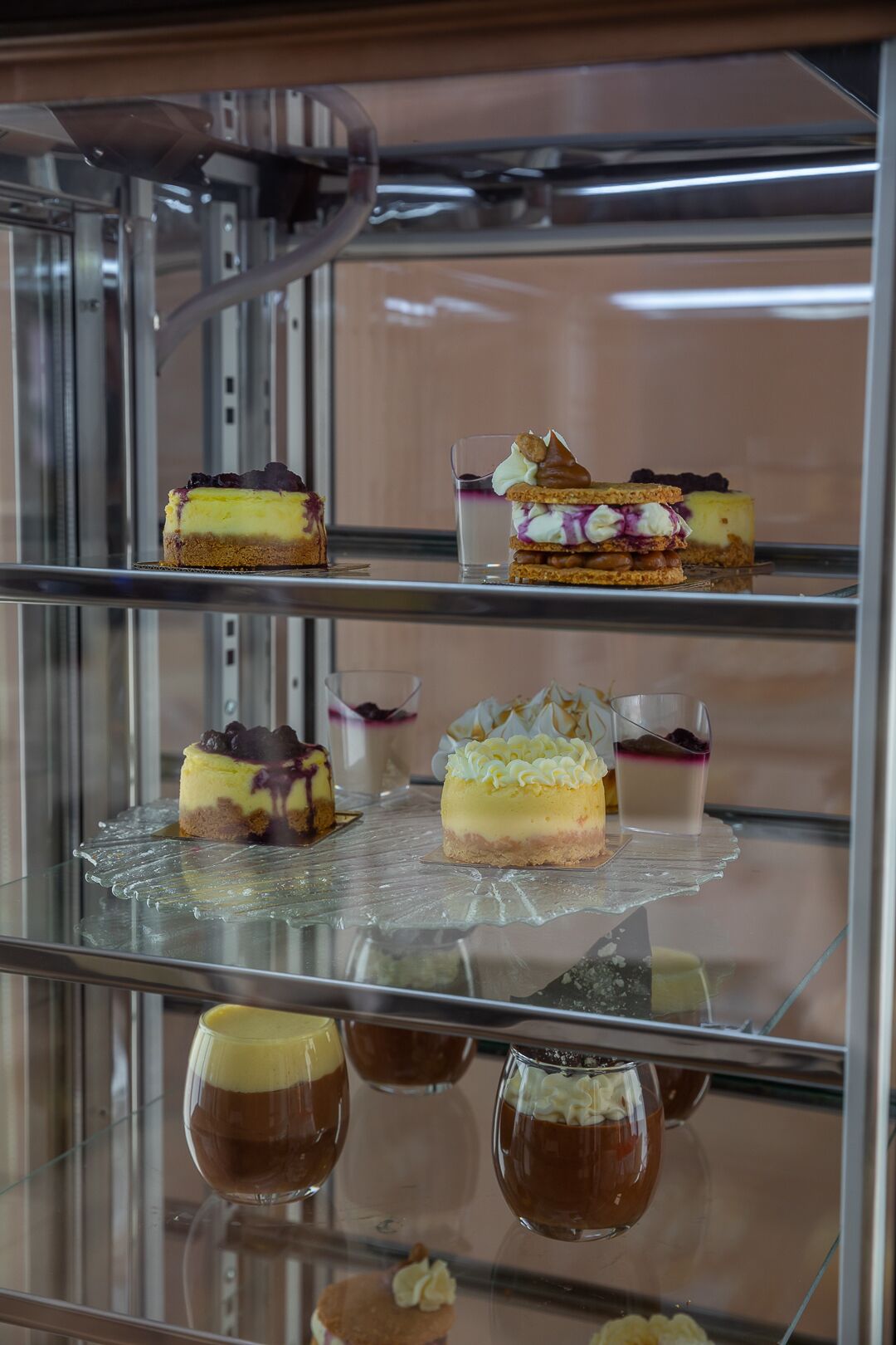 A dessert display with various cakes and pastries on glass shelves.
