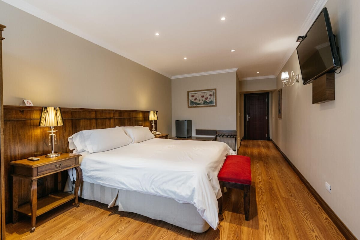 Une chambre d’hôtel avec un grand lit, des tables de chevet avec des lampes, une télévision et un tableau au mur.