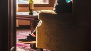 Una habitación con vistas a montañas a través de un ventanal grande, una silla, una botella sobre la mesa y una alfombra en el suelo.