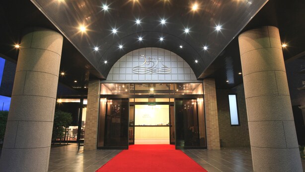 A hotel entrance with a red carpet, a large illuminated sign, and a modern architectural design. - Royal Hotel Uohachi (Toyota)