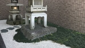 A traditional Japanese garden with a multi-tiered stone lantern, a smaller lantern, and a stone pagoda. - Royal Hotel Uohachi (Toyota)