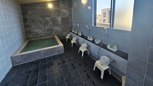 A modern bathroom with a large bathtub, two sinks, and a window providing natural light. - Royal Hotel Uohachi (Toyota)