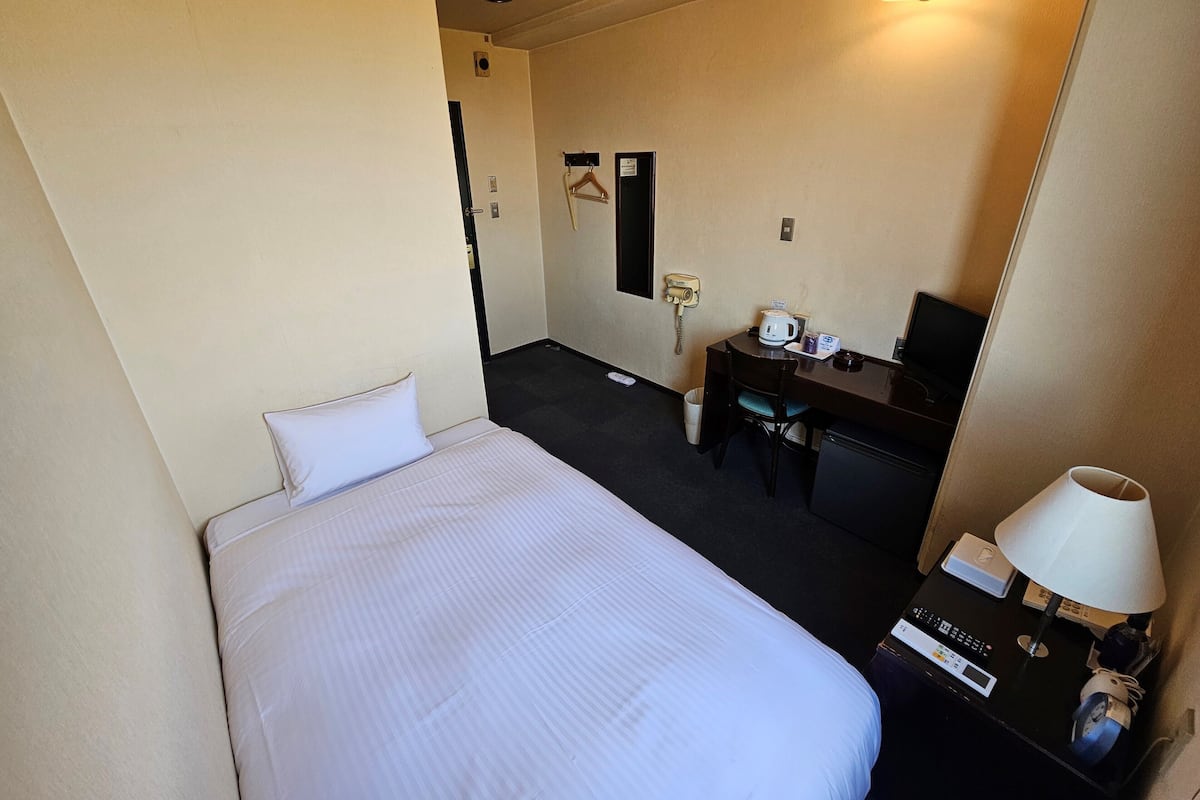 Une chambre d’hôtel équipée d’un lit, d’un bureau, d’une chaise, d’une lampe de bureau, d’un téléphone et d’un téléviseur.