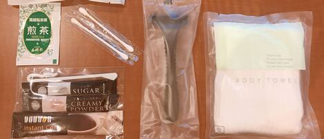A variety of personal care items including a hair brush, toothbrush, body towel, instant coffee, sugar, and creamy powder.