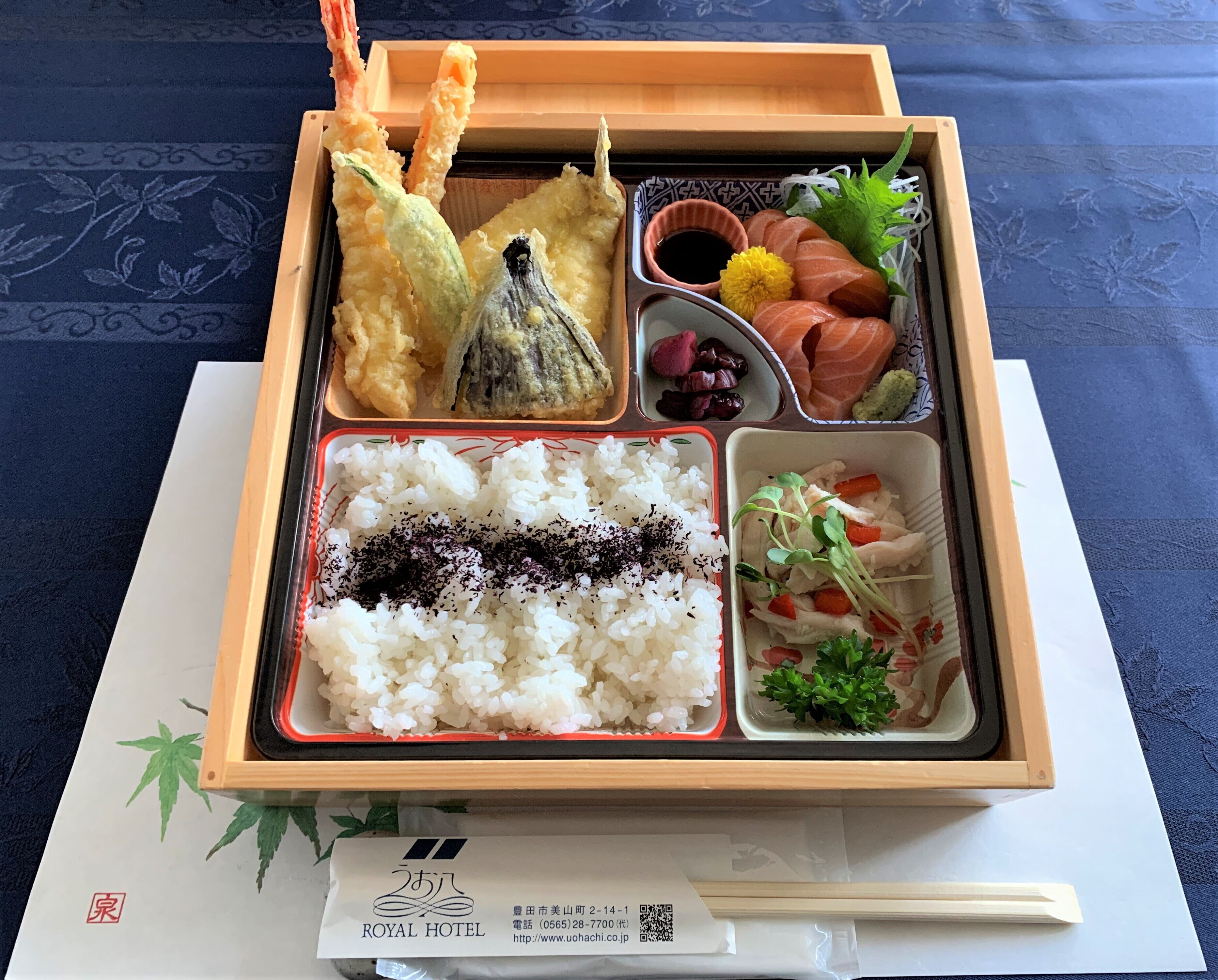 A bento box with rice, fish, and vegetables on a table.
