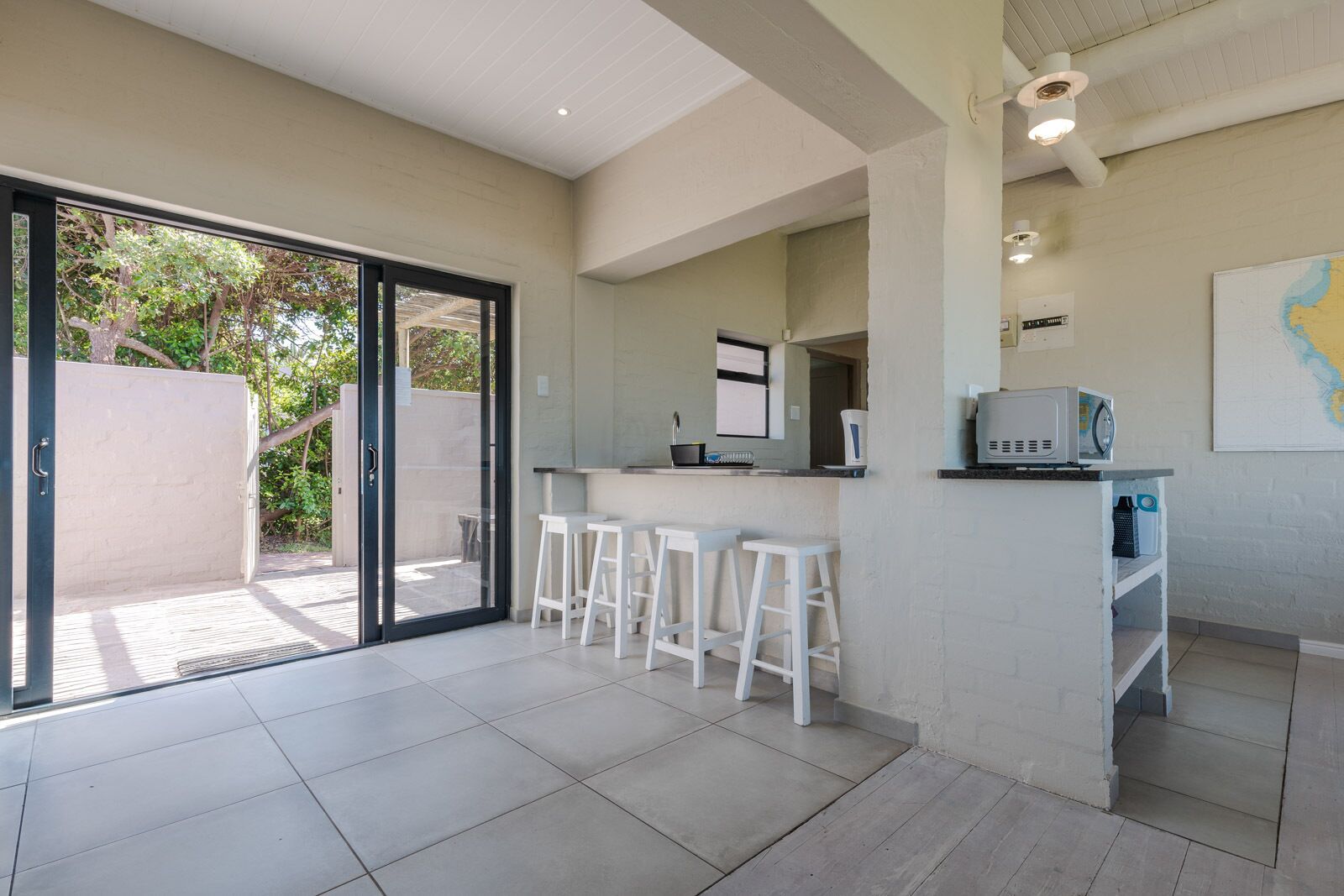 A modern kitchen with a bar area, large sliding glass doors, and a view of the outdoors.