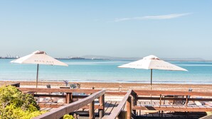 A beachside deck with wooden seating and two umbrellas labeled "Blue Bay Hotel". - Blue Bay Lodge (Saldanha)