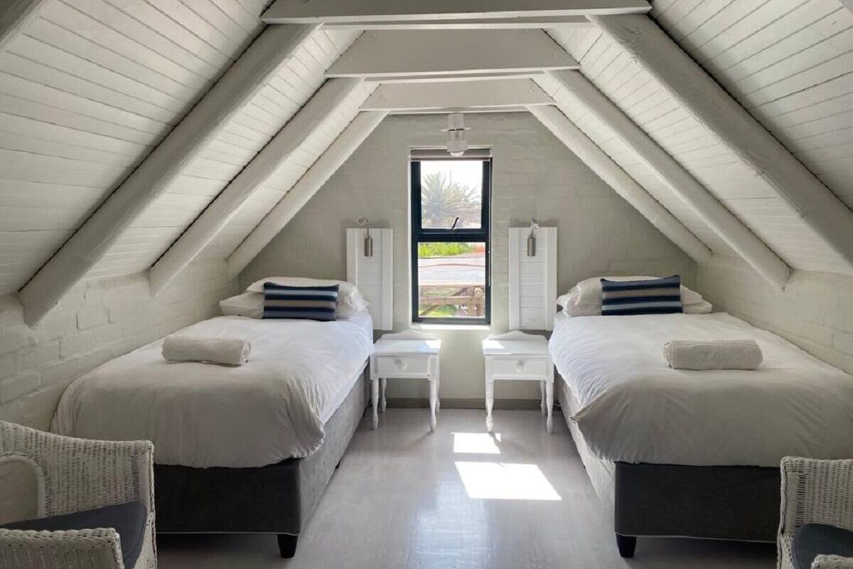 A bedroom with two beds, a window, and a view of the outdoors.