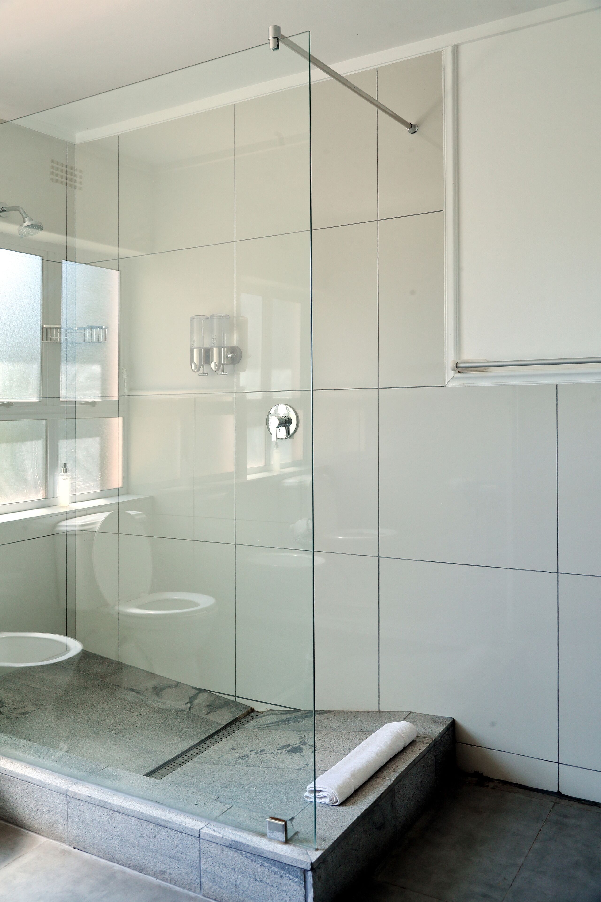Un baño moderno con ducha envuelta en vidrio, inodoro y lavamanos.