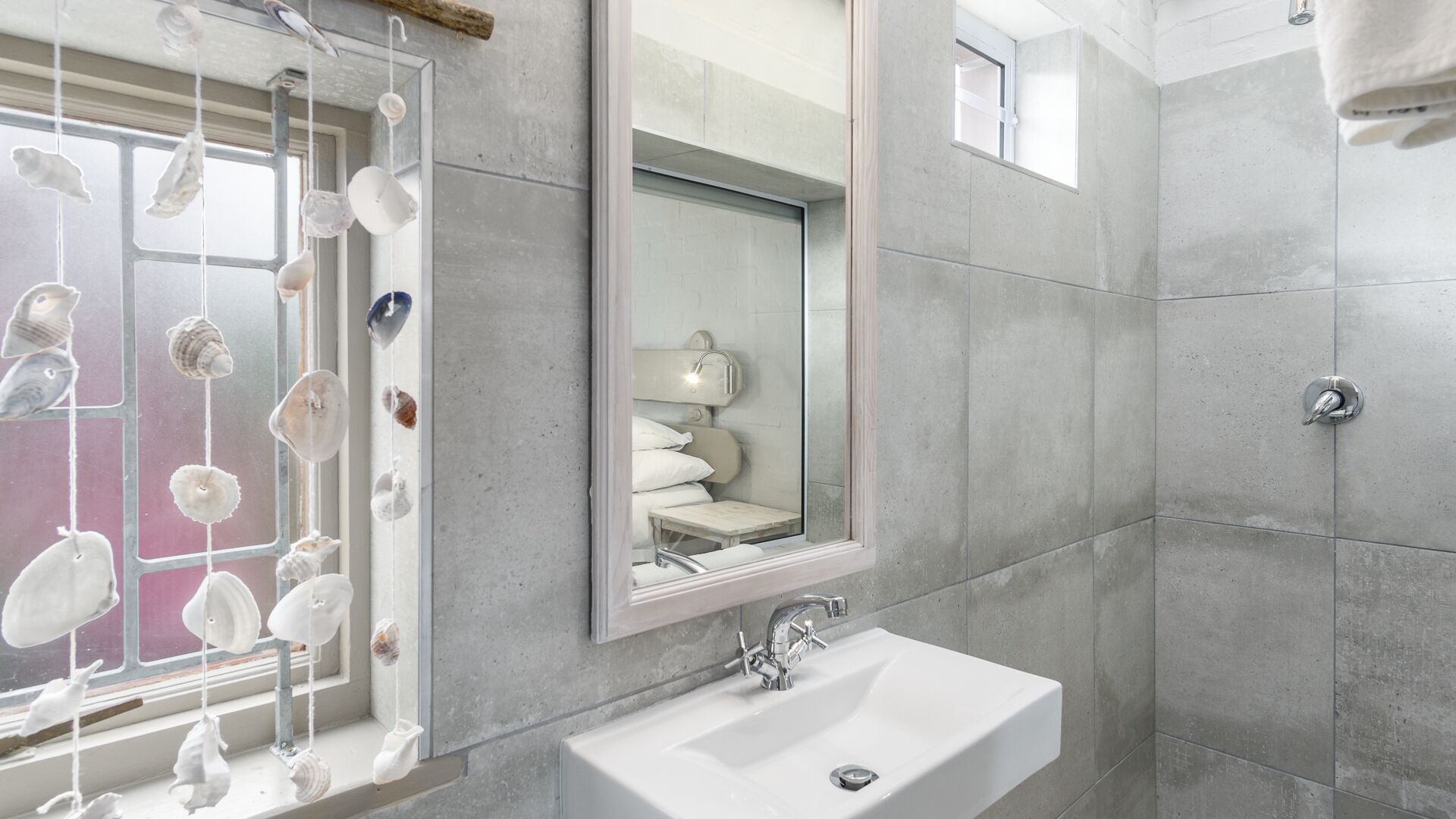 Une salle de bain moderne avec un grand miroir, un lavabo et un espace douche.