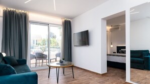 Een moderne woonkamer met een bank, een klein rond tafeltje en een aan de muur bevestigde televisie.