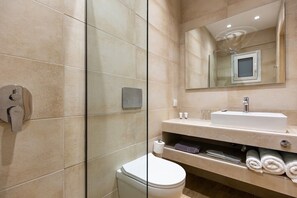 A modern bathroom with a glass shower enclosure, a white sink, and a toilet.