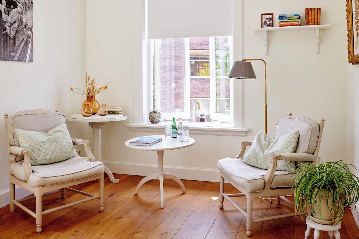 A cozy room with two chairs, a small table, a lamp, and a bookshelf.