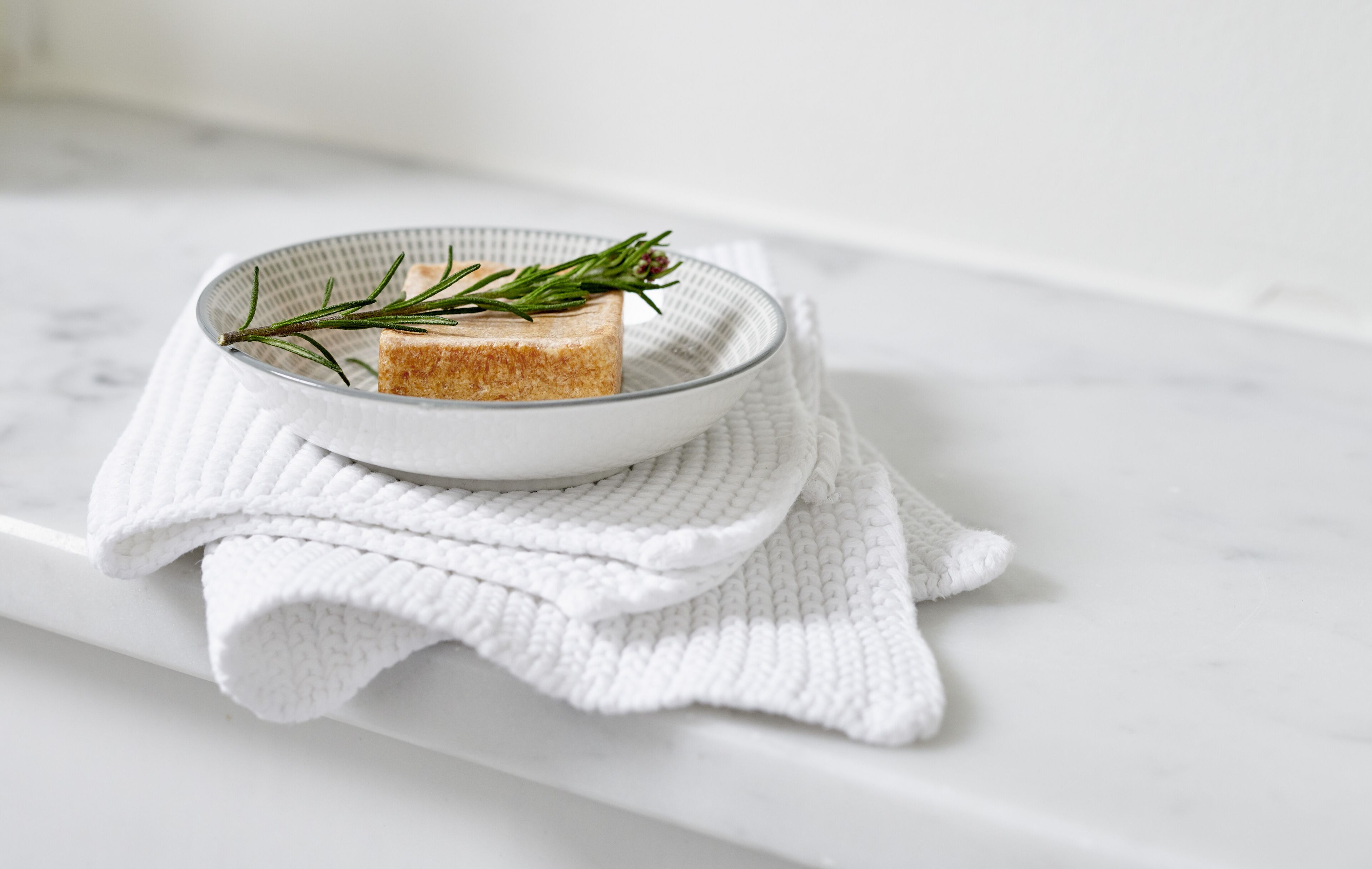Un tessuto bianco e strutturato su una superficie di marmo bianco.