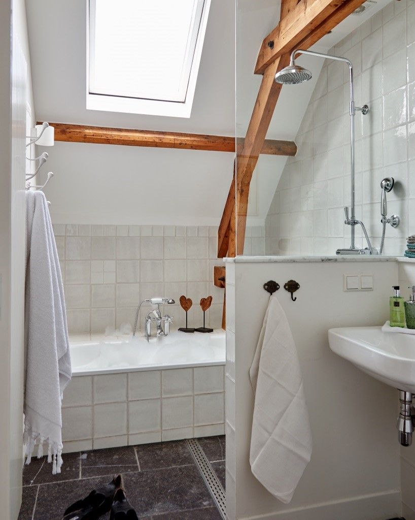 Ein Badezimmer mit Oberlicht, einer Badewanne, einer Dusche und einem Waschbecken.