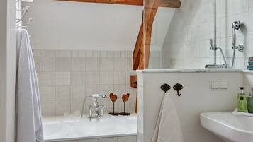 Ein Badezimmer mit Oberlicht, einer Badewanne, einer Dusche und einem Waschbecken.