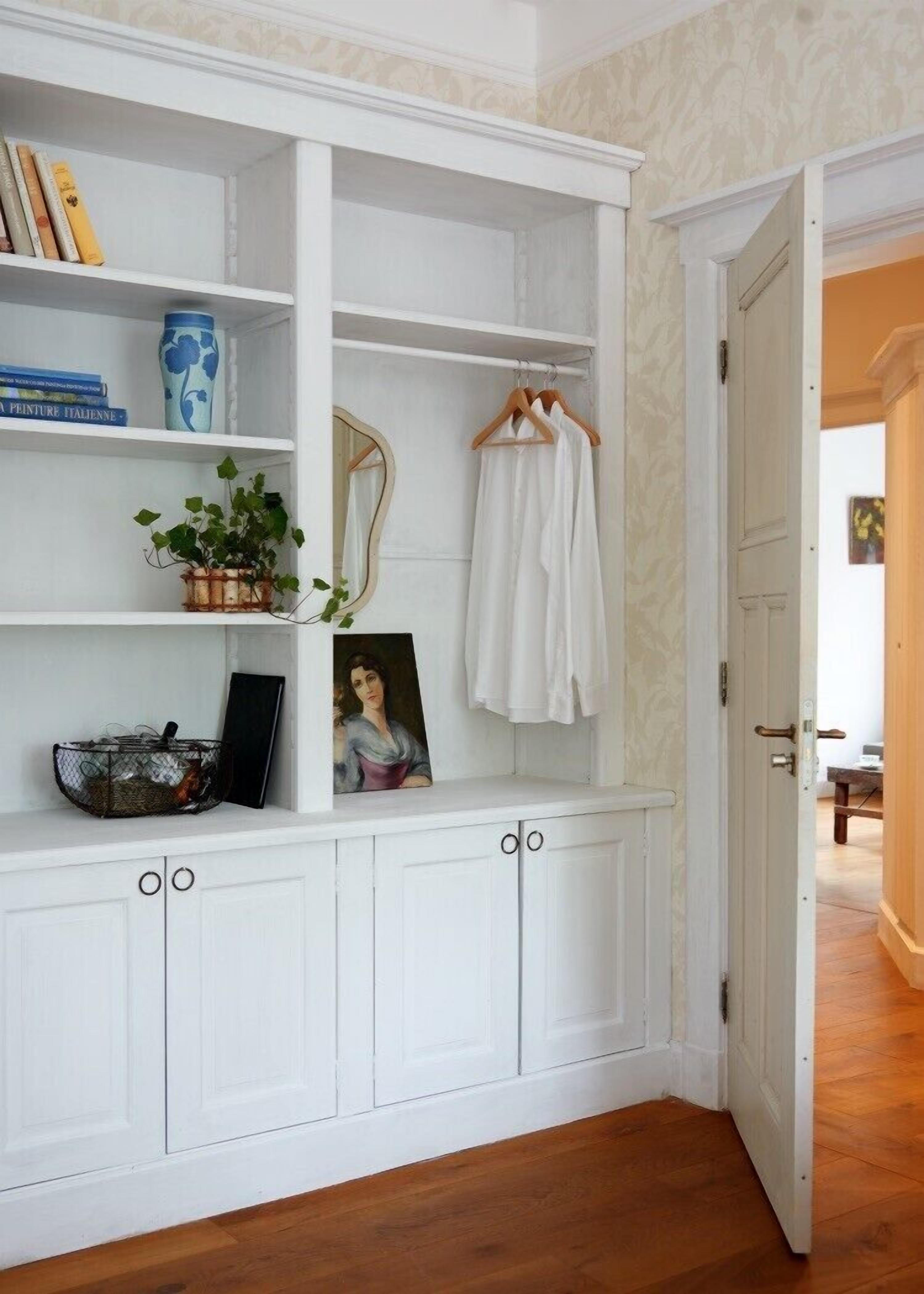 A white built-in shelving unit with books, a vase, and a hanging garment.