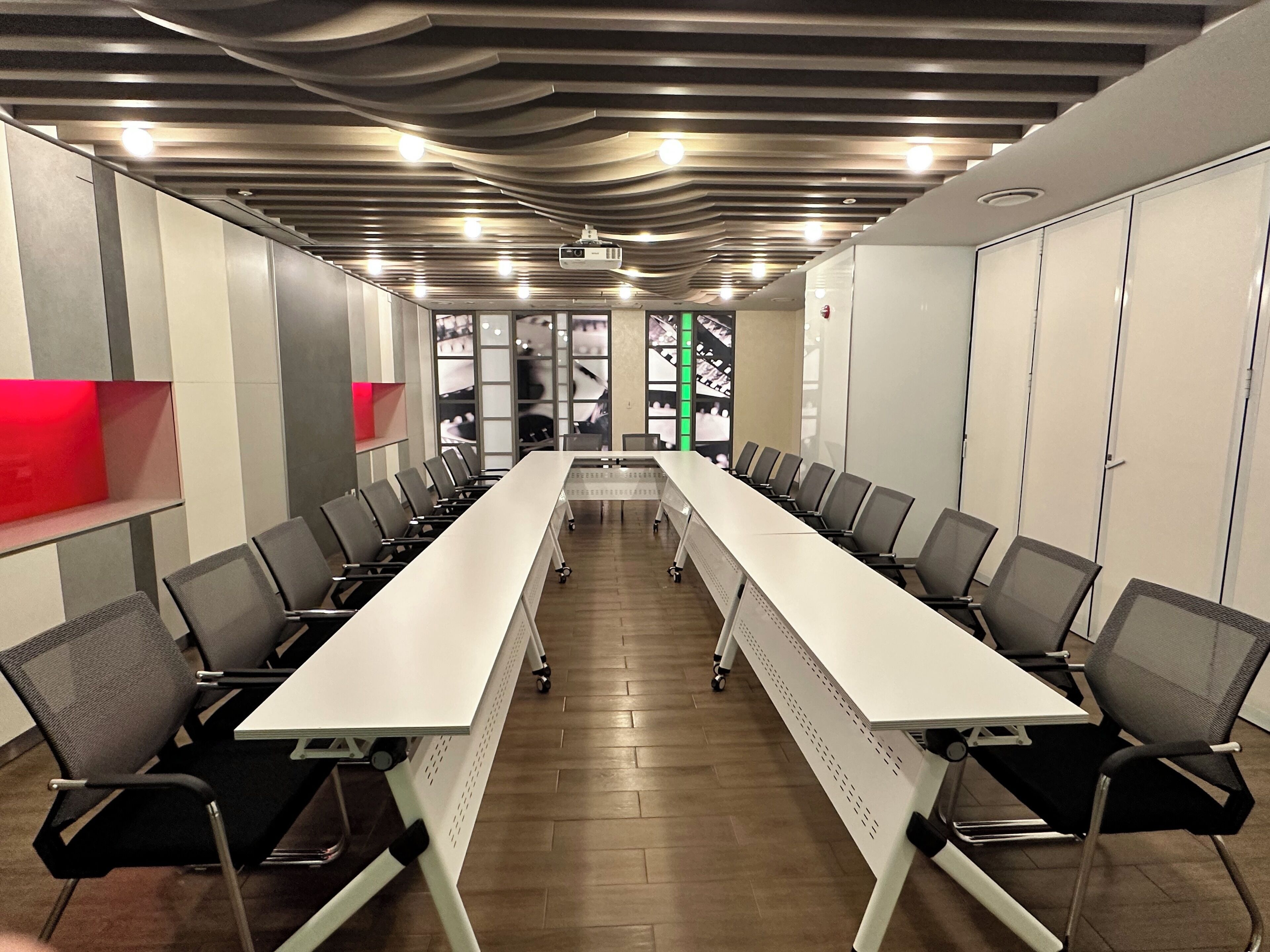A conference room with a long table, chairs, and a projector screen.