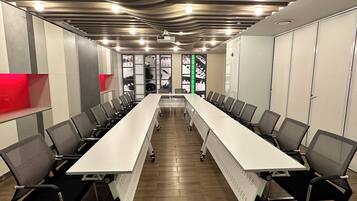 A conference room with a long table, chairs, and a projector screen.