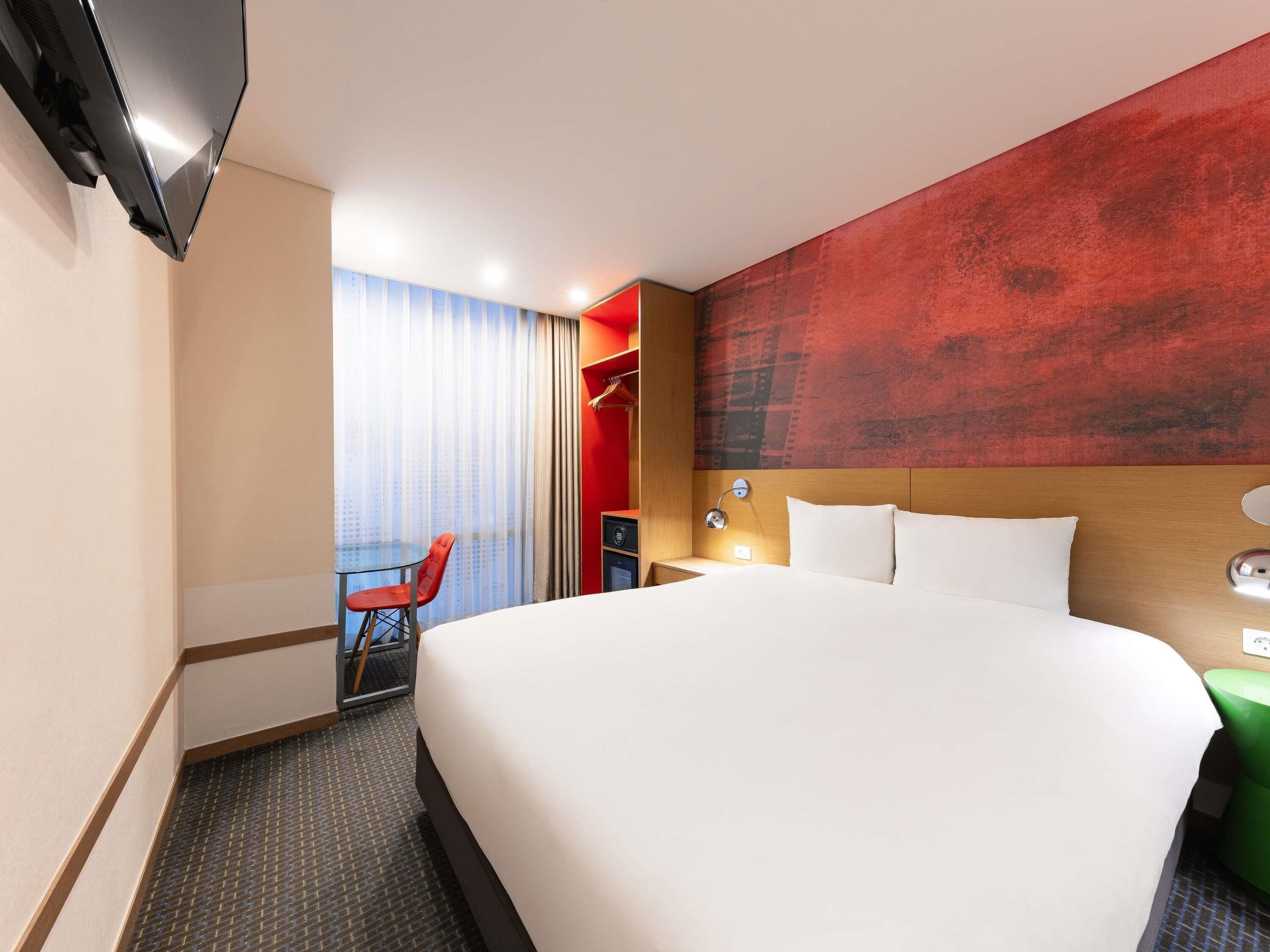 Una habitación de hotel con una cama grande, un escritorio, una silla y un televisor.